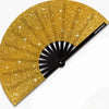 A golden glitter hand fan with a black handle and pleated fan blades.