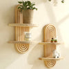 A set of wooden arc wall shelves featuring a rustic floating design, holding a potted plant and a candle.