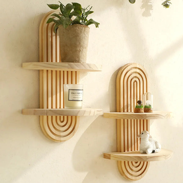 A set of wooden arc wall shelves featuring a rustic floating design, holding a potted plant and a candle.