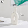 A white minimalist ceramic vase with a narrow neck and rounded body, shown in a side profile.