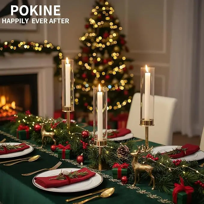 A festive holiday scene featuring gold and silver hurricane candle holders decorated with greenery and gifts.