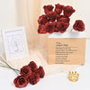 A brown paper bag filled with ten deep red glitter roses and a gold crown.