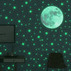 A dark green wall decorated with glowing neon green stars and a large luminous moon.