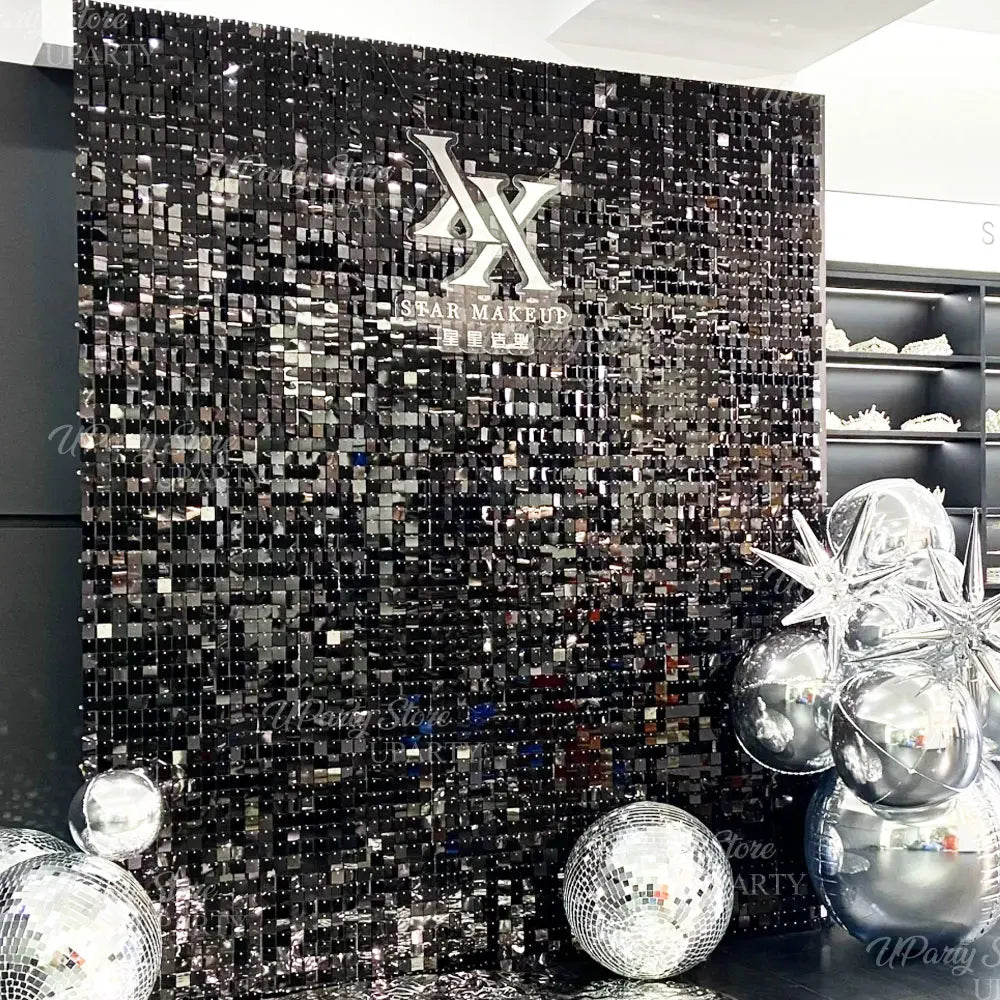 Fond mural en sequins brillants foncés avec un logo 'X' stylisé et des sequins argentés et noirs.