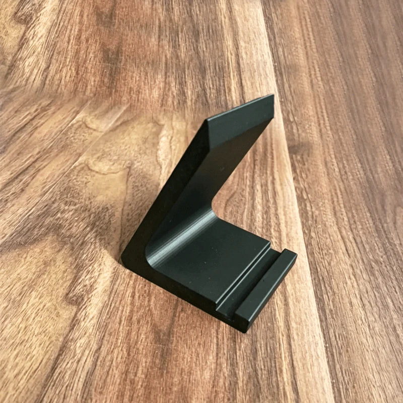 A black minimalist vinyl record and CD display stand resting on a wooden surface.