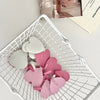 A collection of pink heart-shaped adhesive hooks in various sizes is displayed in a white mesh basket.