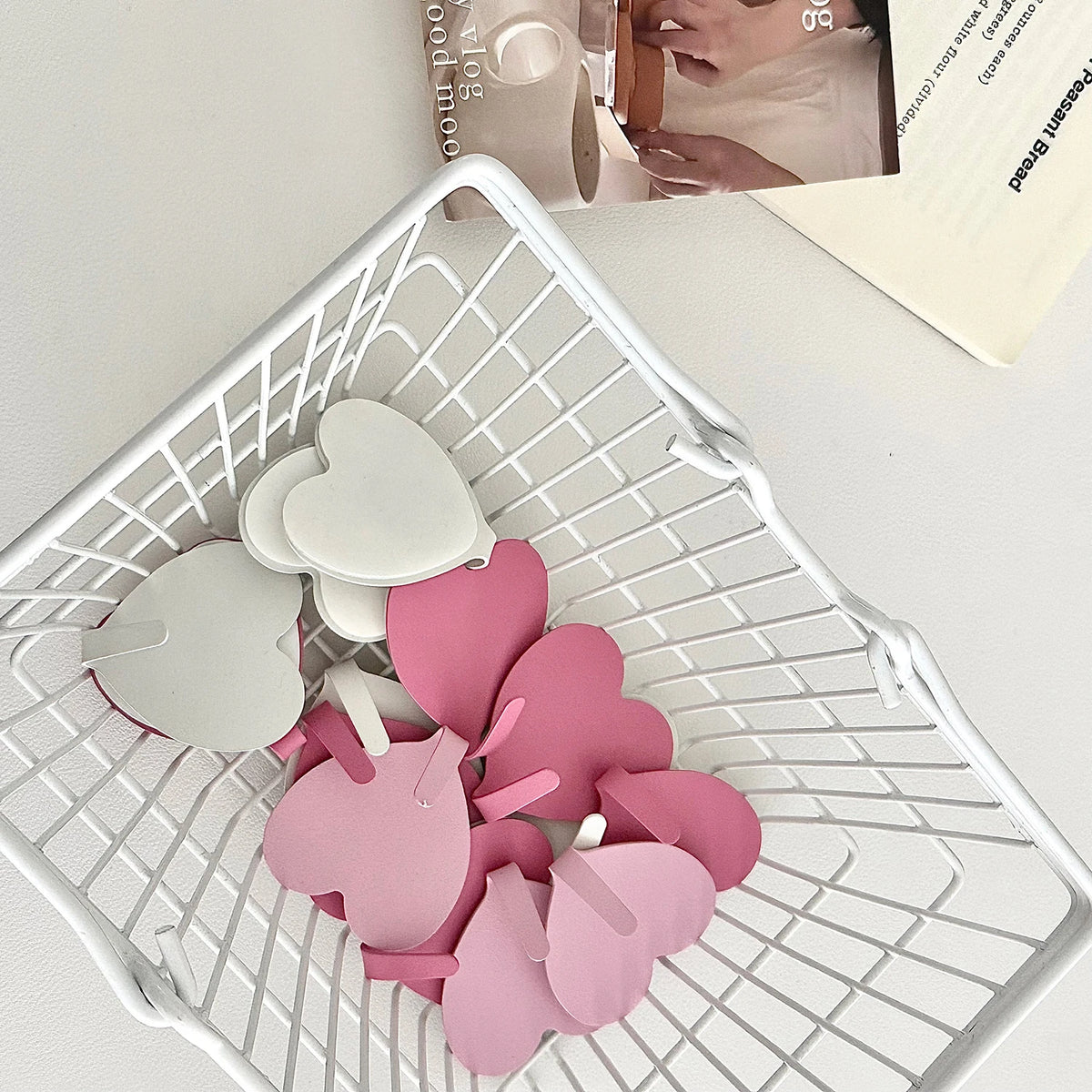 A collection of pink heart-shaped adhesive hooks in various sizes is displayed in a white mesh basket.