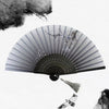 A vintage bamboo folding hand fan with delicate floral accents and a feather detail.
