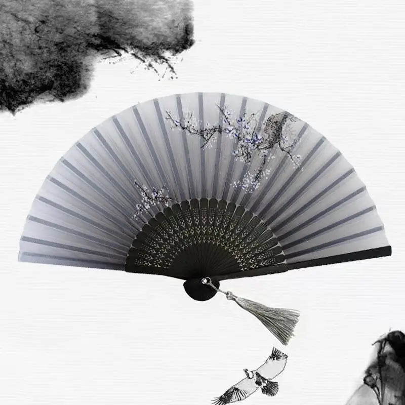 A vintage bamboo folding hand fan with delicate floral accents and a feather detail.