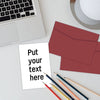 A white card with the text Put your text here is placed on a desk next to a red envelope and several pens.