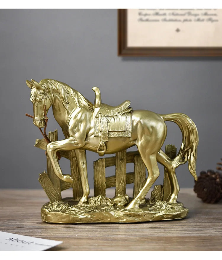 A golden sculpture of a horse with a saddle standing on a wooden fence and landscape.