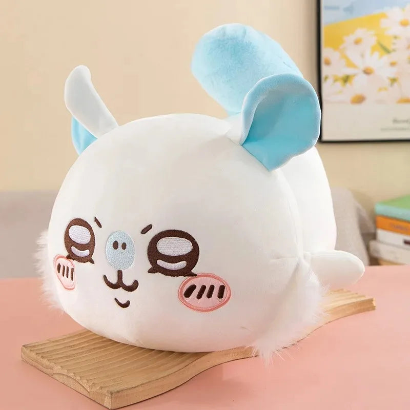 A white Chiikawa Hachiware plush pillow with blue ears and cute facial features resting on a wooden surface.