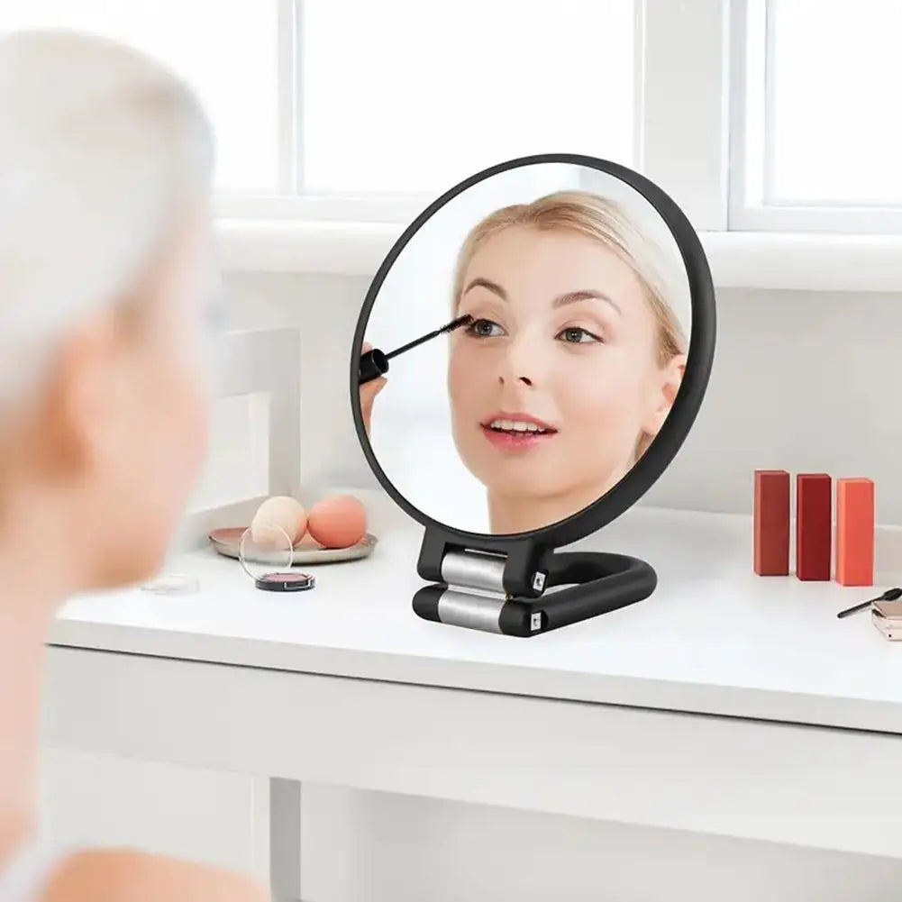 A woman is using a precision dual-magnification handheld mirror to examine her face.