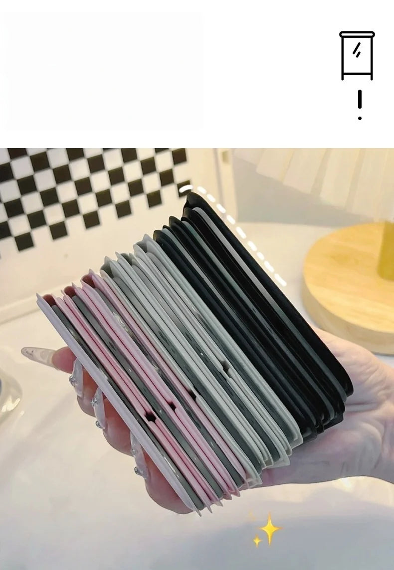 A hand holds a stack of portable folding HD makeup mirrors with various colored frames.
