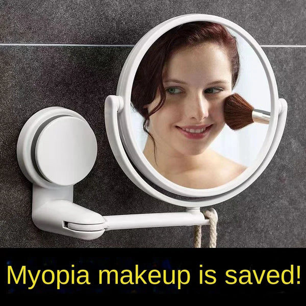 A white, round vanity mirror with a rotating lens is mounted on a gray wall, showing a woman's face.