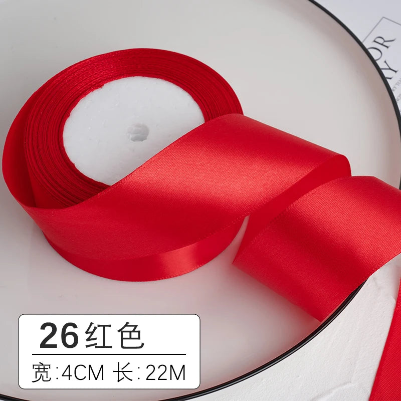 Un rouleau de ruban décoratif en satin rouge, mesurant 4 cm de largeur et 22 mètres de long.