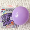 A purple latex balloon is shown next to a package of pastel pink balloons for party decorations.