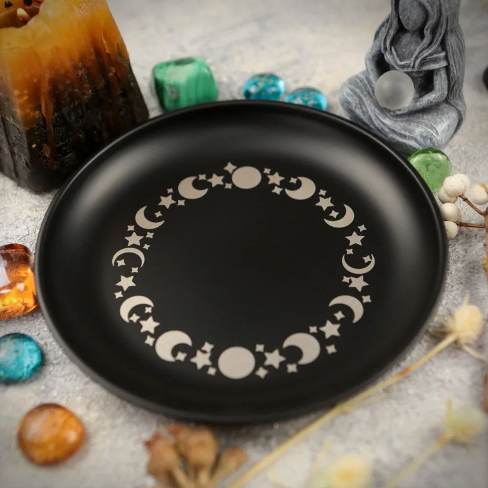 Assiette décorative noire avec couronne de croissant et étoile argentée, entourée de cristaux et de fleurs séchées.