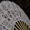 Close-up of an elegant white lace folding hand fan with radiating ribs.