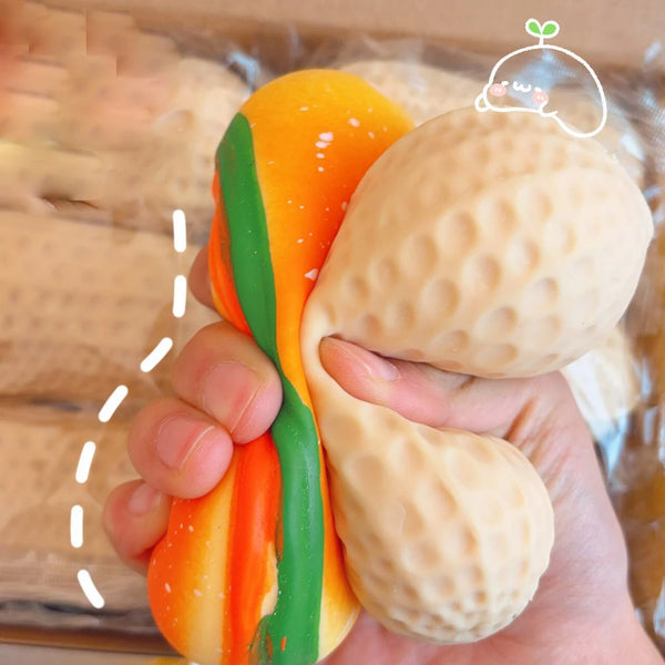 A hand holds an orange and green squishy stress ball shaped like a carrot, next to a beige one.
