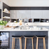 A wooden hanging sign with kitchen rules displayed on a counter in a modern kitchen setting.