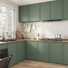 A modern kitchen cabinet setup with sage green cabinetry, light wood countertops, and a stainless steel hood.