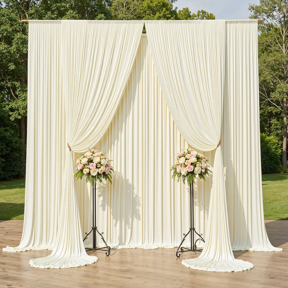 A cream satin backdrop curtain with vertical pleats and floral arrangements used for parties and photography.