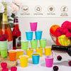 A variety of colorful disposable plastic shot cups in pink, green, yellow, and blue are displayed on a white surface.