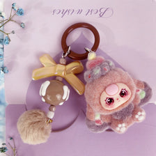 A fluffy pink and gray heart plush keychain charm with a round pink face and a brown leather keyring.