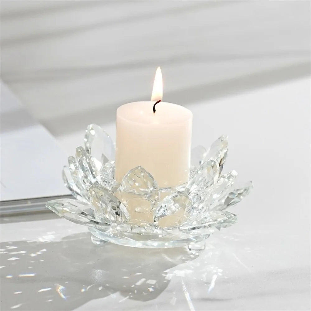 A clear crystal lotus candle holder with a white candle and flame on a marble surface.