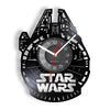 A black wall clock shaped like the Millennium Falcon, featuring a vinyl record design and a red hand.