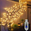 A branch-like LED vine string light display mounted on a wall, illuminated with warm white lights.