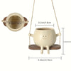 A light beige resin succulent planter hanging from a cord with a wooden swing base.