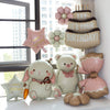 A set of matte 3D heart love-you bear foil balloons in pink and cream colors arranged on a white surface.