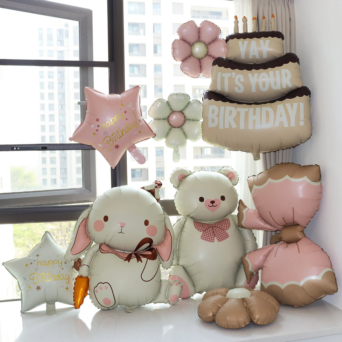 A set of matte 3D heart love-you bear foil balloons in pink and cream colors arranged on a white surface.