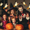 A family of four celebrating Halloween with floating LED candles and a magic wand remote