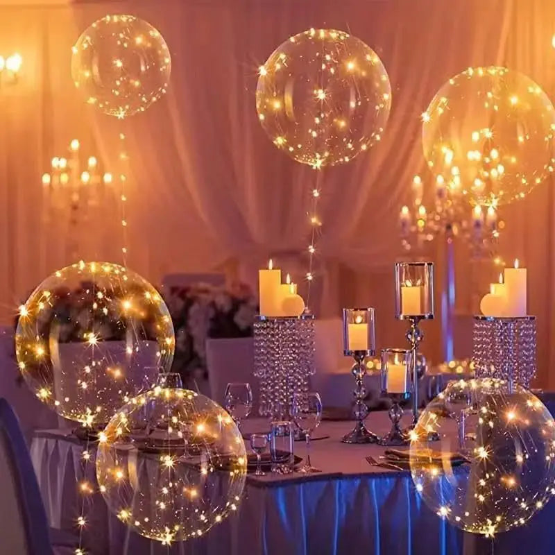 A table setting decorated with LED light-up balloons and warm glow string lights in a soft, elegant atmosphere.