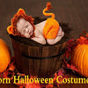 A newborn baby wearing an orange crocheted lion costume resting in a pumpkin basket surrounded by autumn leaves.