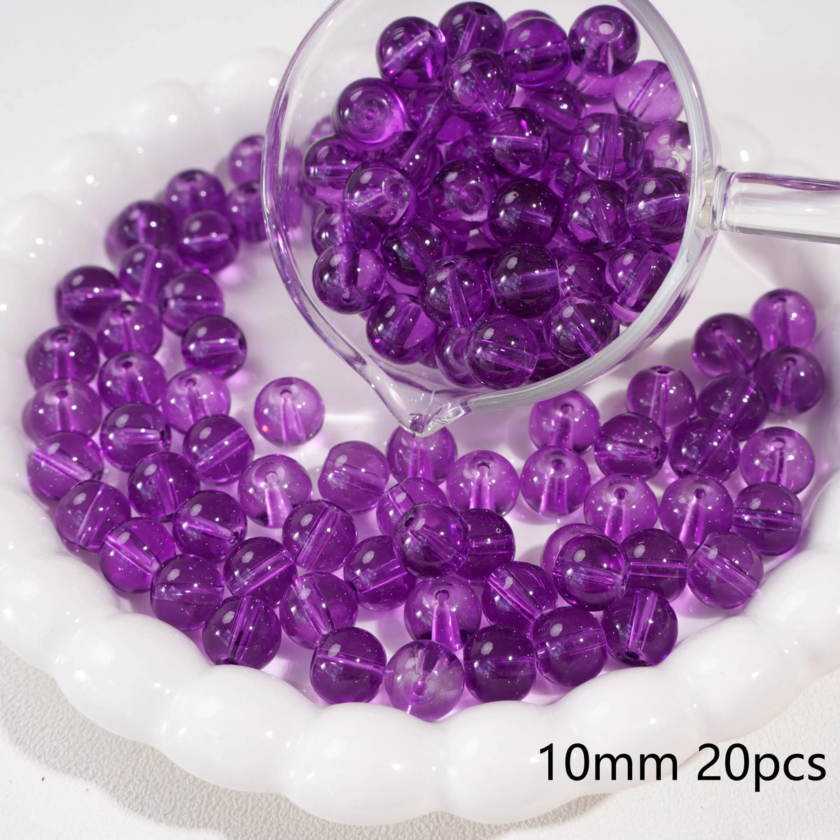 A clear glass measuring spoon holds purple round spacer beads for jewelry making