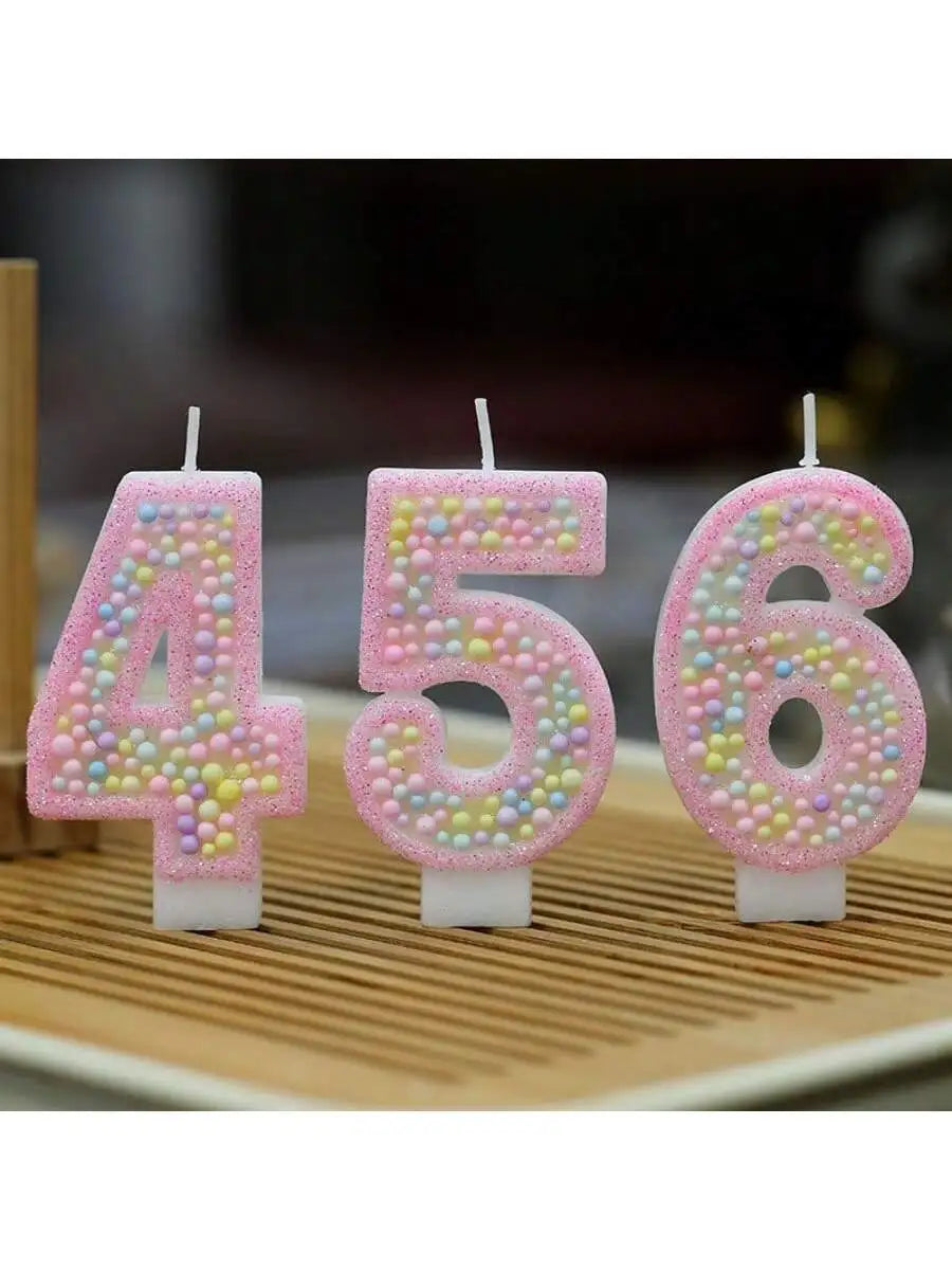 A set of pink macaron number birthday candles displaying the numbers 4, 5, and 6.