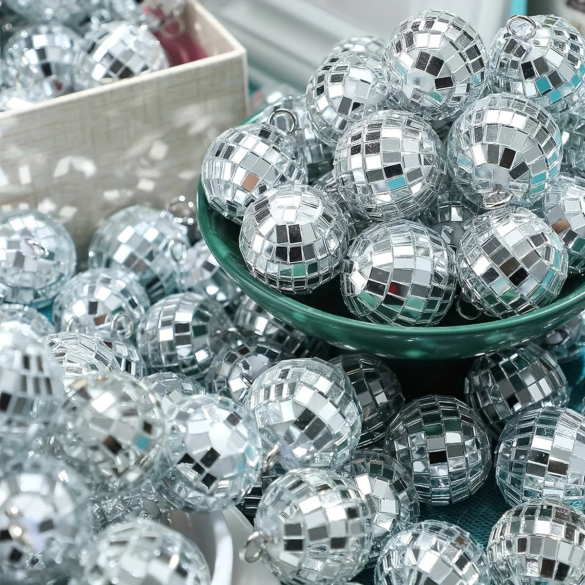A close-up view of a pile of silver and clear mini disco ball ornaments in various sizes and shapes.