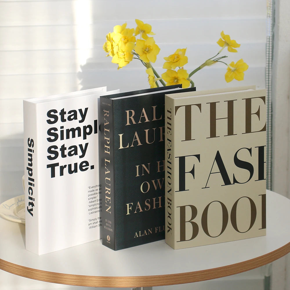 A set of three modern decorative fake books, including a white book, a black book titled Ralph Lauren, and a beige book title