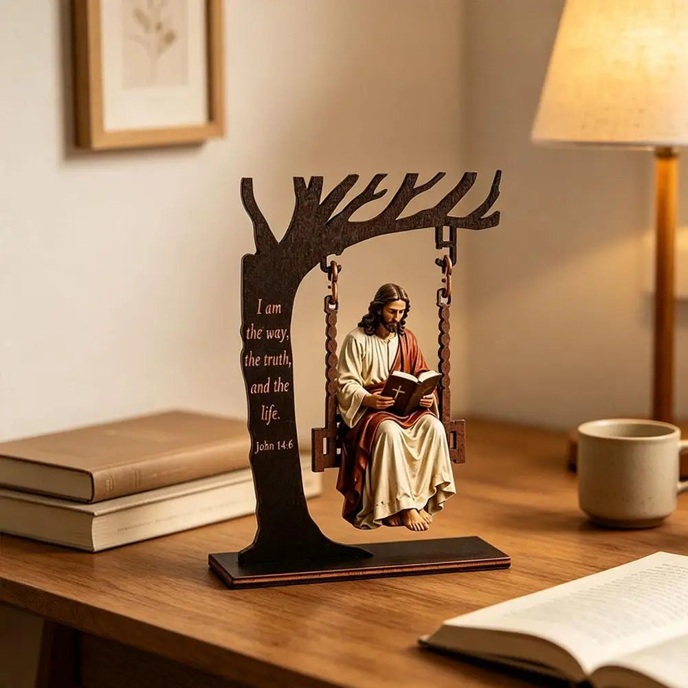 Wooden silhouette of a tree branch forms a swing for a small statue of Jesus reading from the Bible