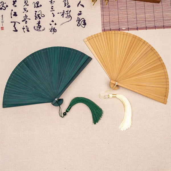 A dark green bamboo folding fan and a light wood-colored bamboo folding fan are displayed on a neutral background.