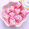 Pink sweet shaped resin candy cabochons for crafting and DIY projects arranged in a pink dish.