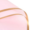 Pink wrapping paper with gold edges and decorative lines shown from a close angle.