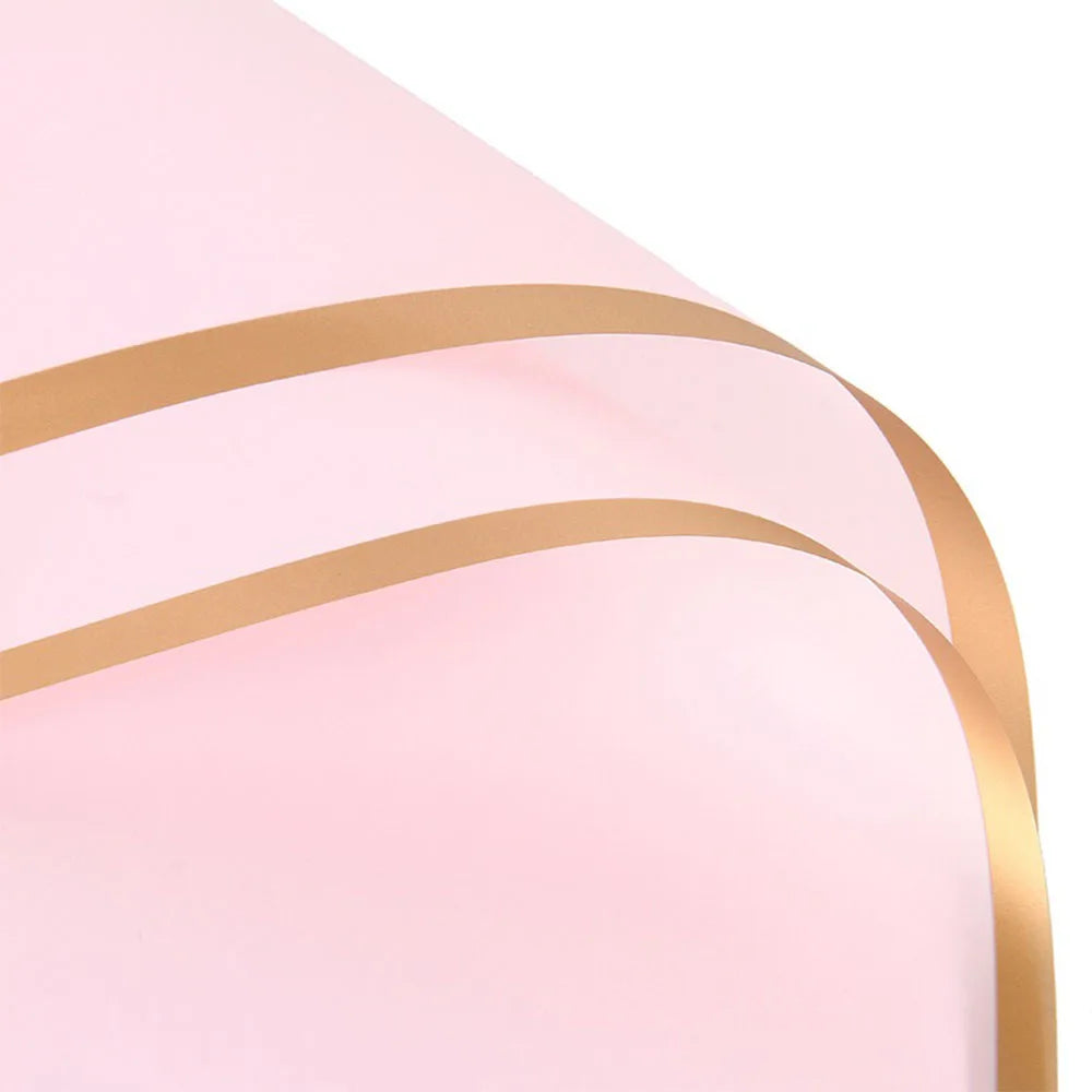 Pink wrapping paper with gold edges and decorative lines shown from a close angle.