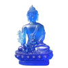 A blue resin statue of the Medicine Buddha seated in meditation with hands in a gesture and a lotus base.