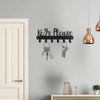A black wall-mounted metal key holder with hooks is displayed on a gray wall above a white door.
