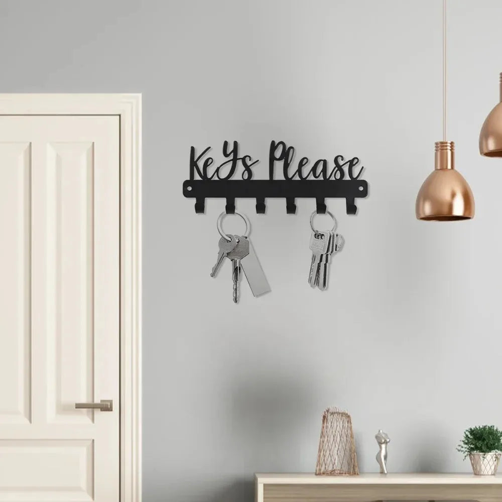 A black wall-mounted metal key holder with hooks is displayed on a gray wall above a white door.